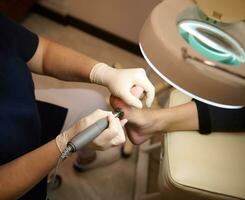 alto ángulo ver de mujer pie durante profesional pies tratamiento en uña salón. pedicure y uña cuidado conceptos foto