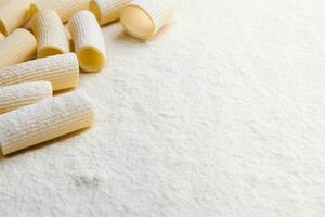 Whole wheat Italian pasta - uncooked tortiglioni- in the corner of a white coloured background with copy space for food advertisement photo