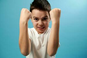 hermoso niño irritado y enojado, expresa negativo emociones, irritación en un azul antecedentes con Copiar espacio. foto