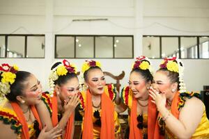 a group of traditional Javanese dancers laughing together with ridiculous faces and full of joy while on stage photo