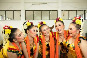 a group of traditional Javanese dancers laughing together with ridiculous faces and full of joy while on stage photo