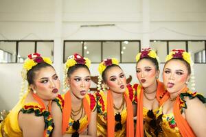 a group of traditional Javanese dancers laughing together with ridiculous faces and full of joy while on stage photo