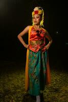 a Javanese dancer poses with sharp eyes and a golden costume on stage photo