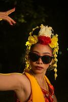 a Javanese dancer dances very skillfully while wearing sunglasses on her eyes and very beautiful facial makeup photo