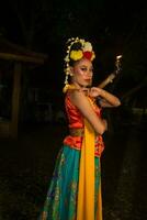 a Javanese dancer poses with sharp eyes and a golden costume on stage photo