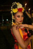 a Javanese dancer poses with sharp eyes and a golden costume on stage photo