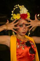 a Javanese dancer poses with sharp eyes and a golden costume on stage photo