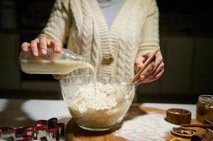 de cerca mujer torrencial planta establecido Leche dentro un cuenco con harina, para preparando masa para Navidad pan de jengibre galletas foto