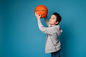 Isolated portrait on blue background of a handsome boy playing basketball photo