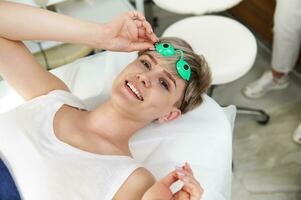 Happy female client of beauty SPA clinic looking at camera with toothy smile and enjoying beauty procedures in SPA center photo