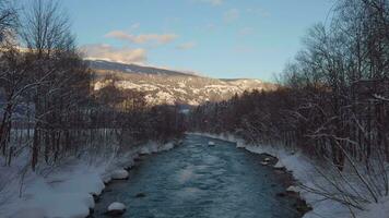 a river in the snow with trees and mountains in the background video