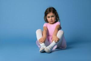 enfocado niña bailarina extensión su piernas antes de rutina de ejercicio en ballet bailando foto