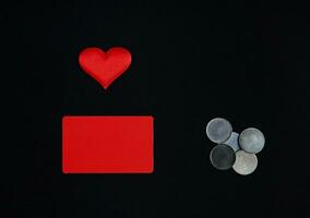 un horizontal rojo rectángulo, rojo corazón y dinero monedas en un negro antecedentes. borde, Copiar espacio, parte superior vista, celebracion, fiesta foto