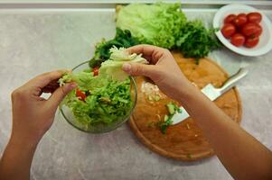 Healthy ingredients for raw vegan salad. Close-up of female chef hands preparing raw vegan salad at home kitchen. Food and concept of veganism, vigor and healthy eating photo