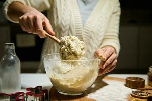 Female pastry chef kneads dough to make gingerbread for Christmas, in a cozy home atmosphere in the kitchen. Concept of delicious homemade sweet cookies photo