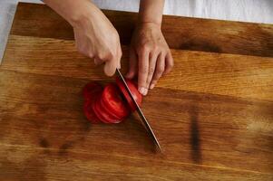 parte superior ver de mujer mano corte tomate en un de madera tablero foto