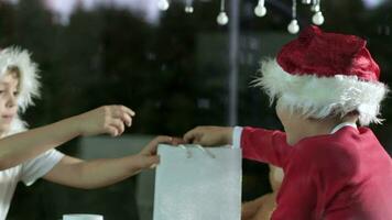 deux les enfants dans Père Noël Chapeaux sont en portant une cadeau sac video