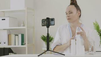une cosmétologue est montrant cosmétique produit et une fonction à le caméra video