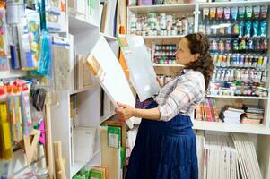 Pregnant female artist standing in the art department of a school stationery store with canvases in her hands photo