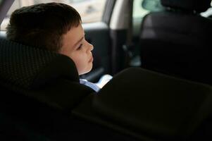 Rear view of a schoolboy in rear passenger seat in the car photo