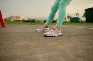 Close-up, cropped view of female legs in sportswear and sports shoes during outdoor workout on the sportsground. Weight loss, active lifestyle, fitness, sport and body care concept photo