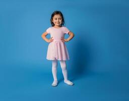 Little ballerina in pink dress posing into the camera with space for text photo