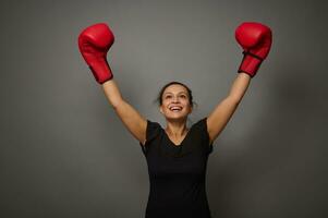 concepto de soplar a precios en gris antecedentes con Copiar espacio. mujer Boxer en negro médico protector máscara y boxeo guantes levanta manos en ganador posición. disparo para boxeo día y negro viernes foto