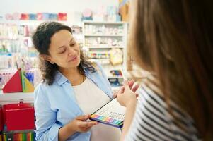 Smiling multi-ethnic woman holding metal case with colored pencils, shopping for school stationery in creative art store photo