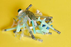 Stack of different syringes with beauty injections lying on yellow background with copy space. Shot with light shadow. photo