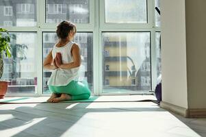 Side view of a sportswoman crossing her arms behind her back, thereby performing a body stretch photo