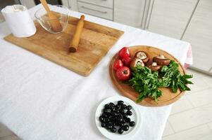 High angle view of ingredients for pizza on wooden kitchen board on a table. photo