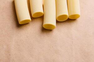 Top view of one type of pasta on a craft paper surface with copy space. Raw tortiglioni and cannelloni photo