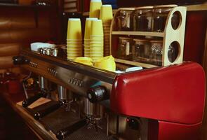 Yellow takeaway cardboard cups inverted on a steam coffee machine. Closeup of espresso and coffee maker. photo