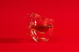 Stack of two transparent glass cups for hot drinks on a red background with copy space. photo