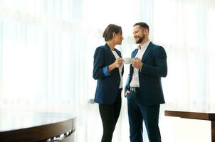 Full-length portrait of business partners, colleagues during a coffee break. Boss and employee flirting at work. The concept of partnership, teamwork and successful leadership at work photo