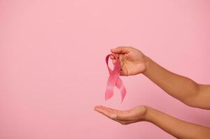 Woman hands holding a pink ribbon, symbol of World Breast Cancer awareness Day, in 1 st October. Woman's health and medical concept, October Pink day, World Cancer Day, national Cancer Survivor Day. photo