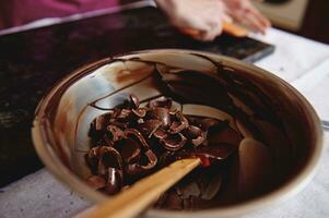 Metal bowl with dark chocolate and cooled melted chocolate mass photo