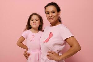 Gorgeous women of two generations, African American lady and European baby girl, in pink clothes and a ribbon, support cancer survivors. Medical Concept October 1. World Breast Cancer Awareness Day photo