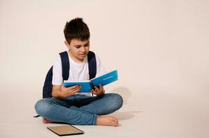 Studio portrait of a smart teenage school boy holding copybook, reading, doing homework over white isolated background photo