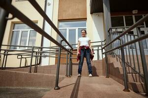 Young woman with skateboard on the background of a yellow building photo