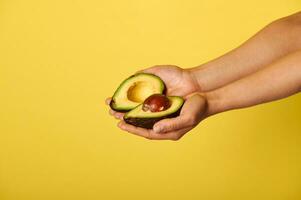 Closeup of hands holding two halves of ripe ready-to-eat avocado photo