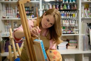 Inspired female artist painting on canvas in her art studio, searching for imagination. Creative hobby and occupation photo