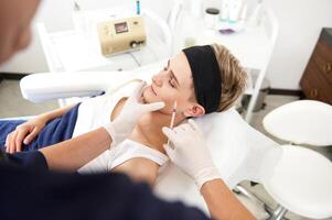 Beautician holding syringe near the face of client of spa center and making beauty injection on her face at beauty SPA center photo