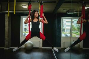 Fit pretty young woman doing fly yoga stretching exercises in a studio. Sport and healthy lifestyle concept photo