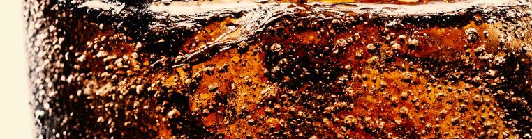 Splashing of Cola and Ice. Cola soda and ice splashing fizzing or floating up to top of surface. Close up of ice in cola water. Texture of carbonate drink with bubbles in glass. Cold drink background photo