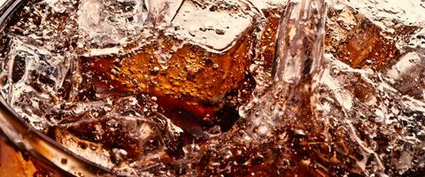 Splashing of Cola and Ice. Cola soda and ice splashing fizzing or floating up to top of surface. Close up of ice in cola water. Texture of carbonate drink with bubbles in glass. Cold drink background photo