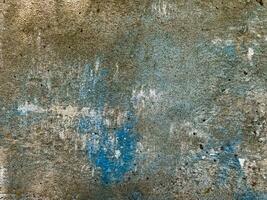 TThe texture of an old concrete wall, painted over with strokes of light brown and blue paint for background and design. Photo