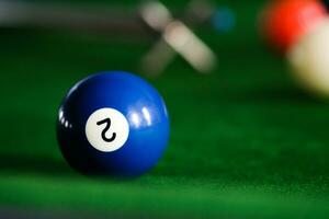 Man's hand and Cue arm playing snooker game or preparing aiming to shoot pool balls on a green billiard table. Colorful snooker balls on green frieze. photo