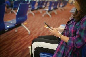 Woman waiting for departure at the airport on your vacation hold passport and smartphone while waiting boarding on departure area International Airport photo