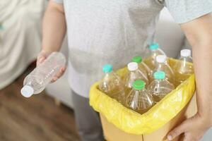 hogar reciclar eco verde cero concepto hombre lanzamiento vacío el plastico botella en reciclaje compartimiento con amarillo basura pantalones a hogar foto